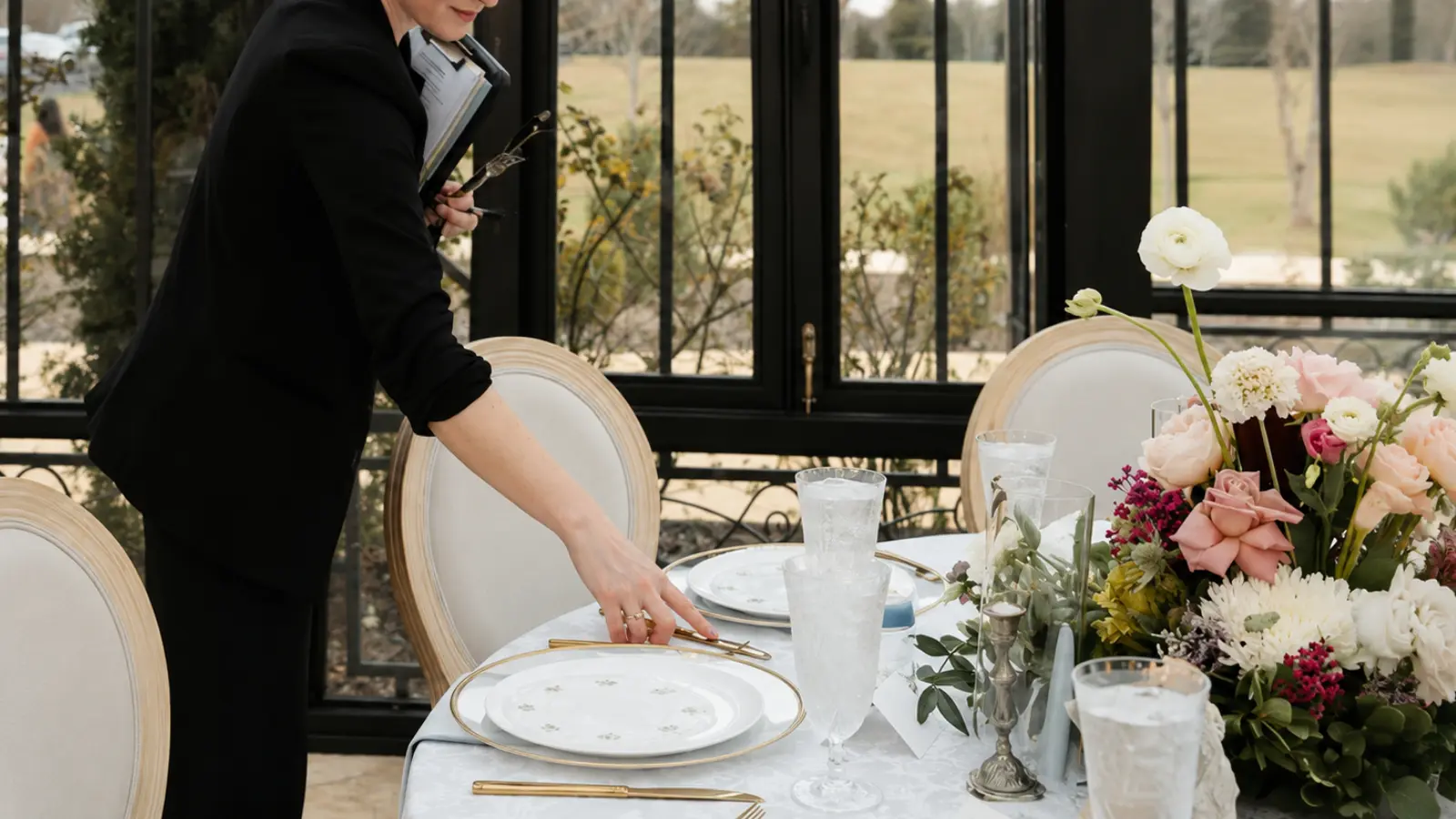 Wedding planner checking place settings and floral details on an elegant luxury wedding reception table before guests arrive
