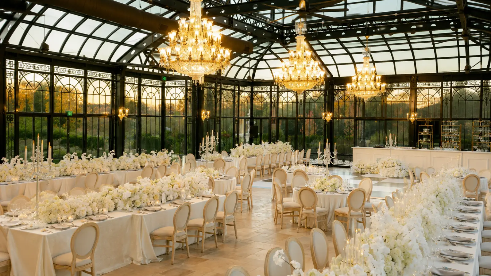 Luxury wedding reception with crystal chandeliers, white floral arrangements, formal dining tables and elegant seating inside a glass venue How to Plan a Luxury Wedding That Feels Effortless