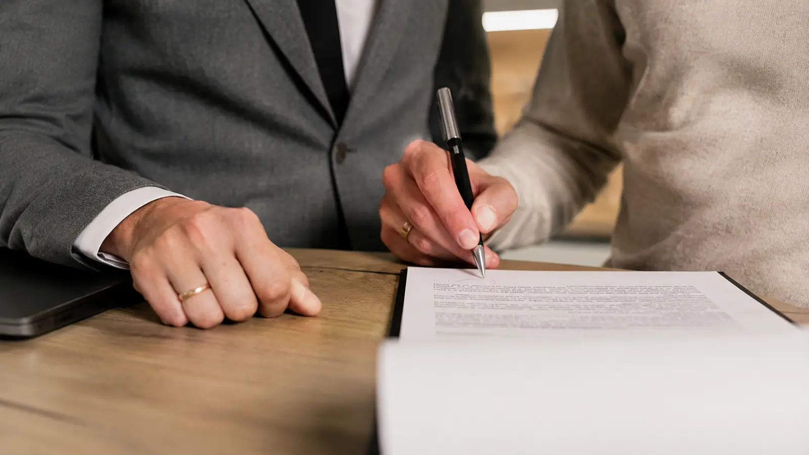 Couple signing marriage license documents together while completing paperwork required under state marriage laws Marriage License by State: Requirements, Waiting Periods and Expiration