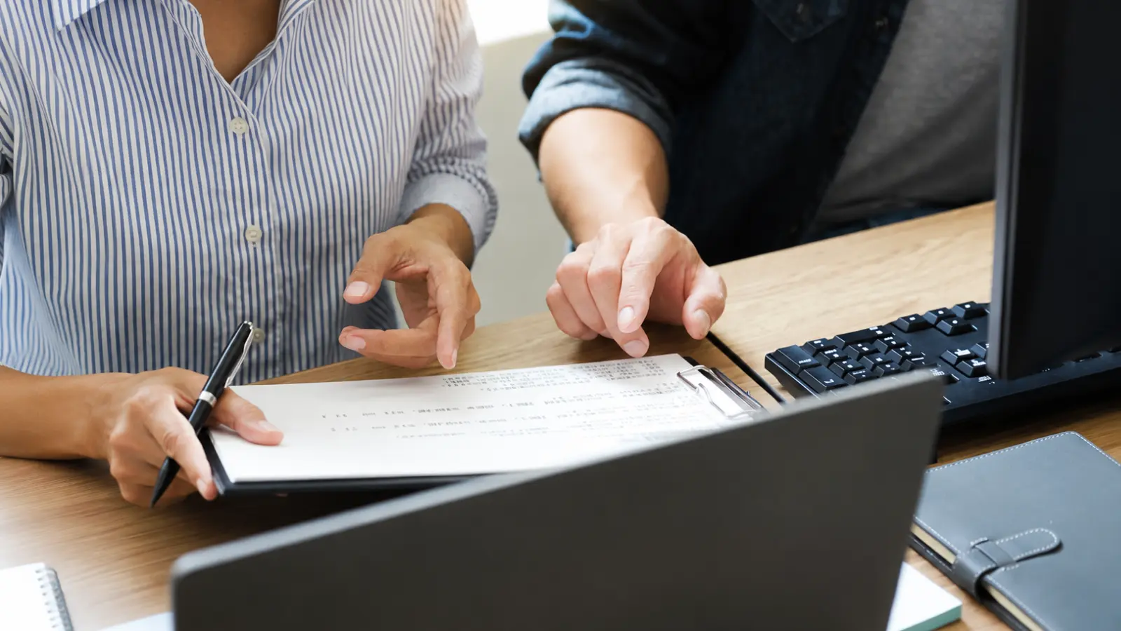 Two people reviewing documents and using a computer while searching for public marriage records Marriage Records: How to Find and Search Public Records