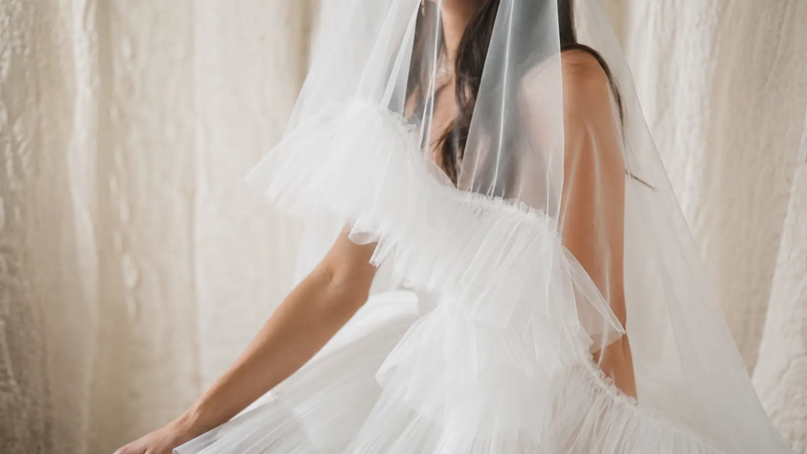 Modern bride wearing a sheer blusher wedding veil over her face with a dramatic ruffled white wedding dress and minimalist bridal styling Blusher Wedding Veil