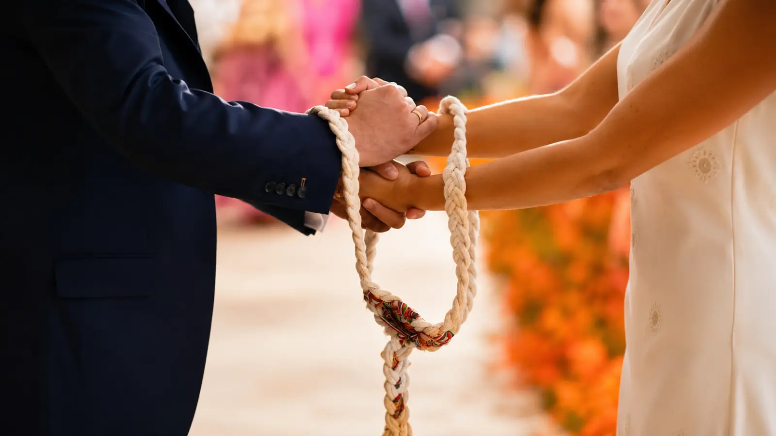 Multicultural wedding couple holding hands during a cultural ceremony ritual with a ceremonial cord joining them together