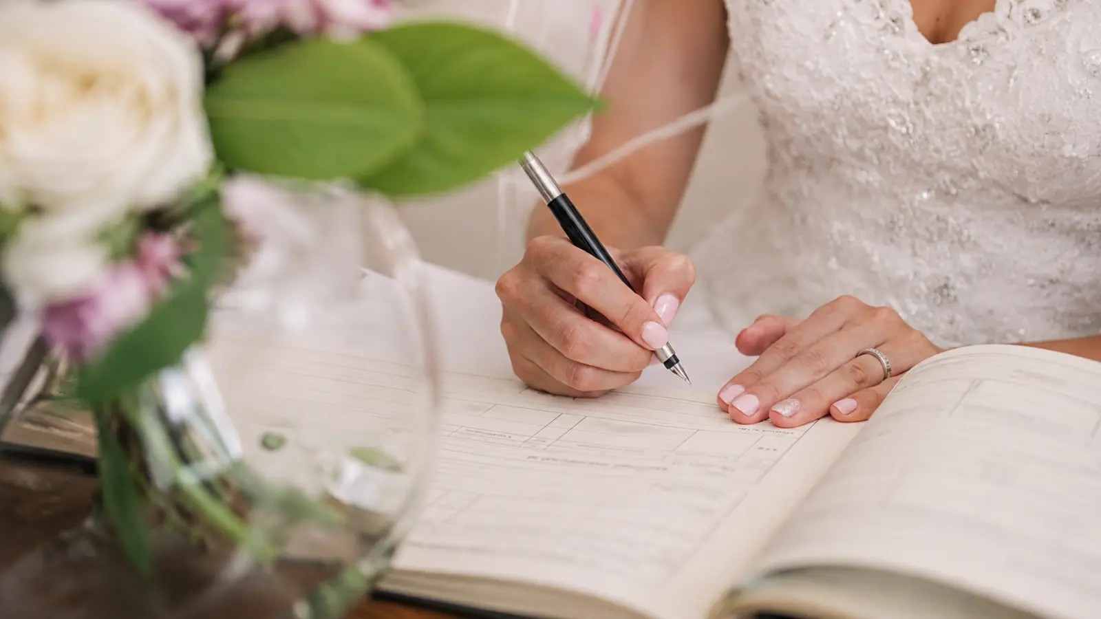 Bride signing marriage documents during a ceremony, illustrating the legal requirements, documentation and recognition involved in a proxy marriage