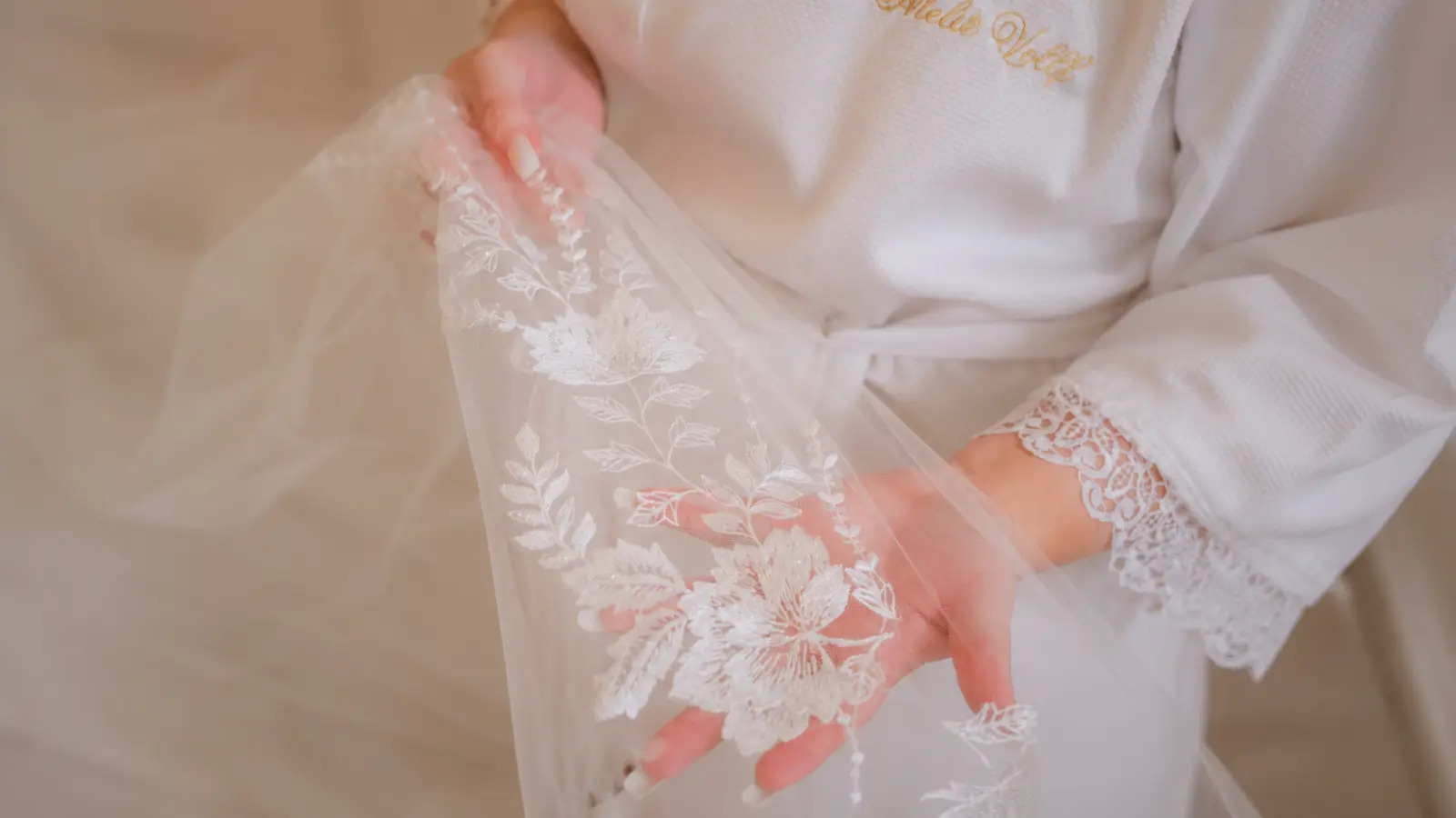 Bride examining embroidered floral lace from her wedding veil as inspiration for preserving or repurposing the delicate fabric after the wedding