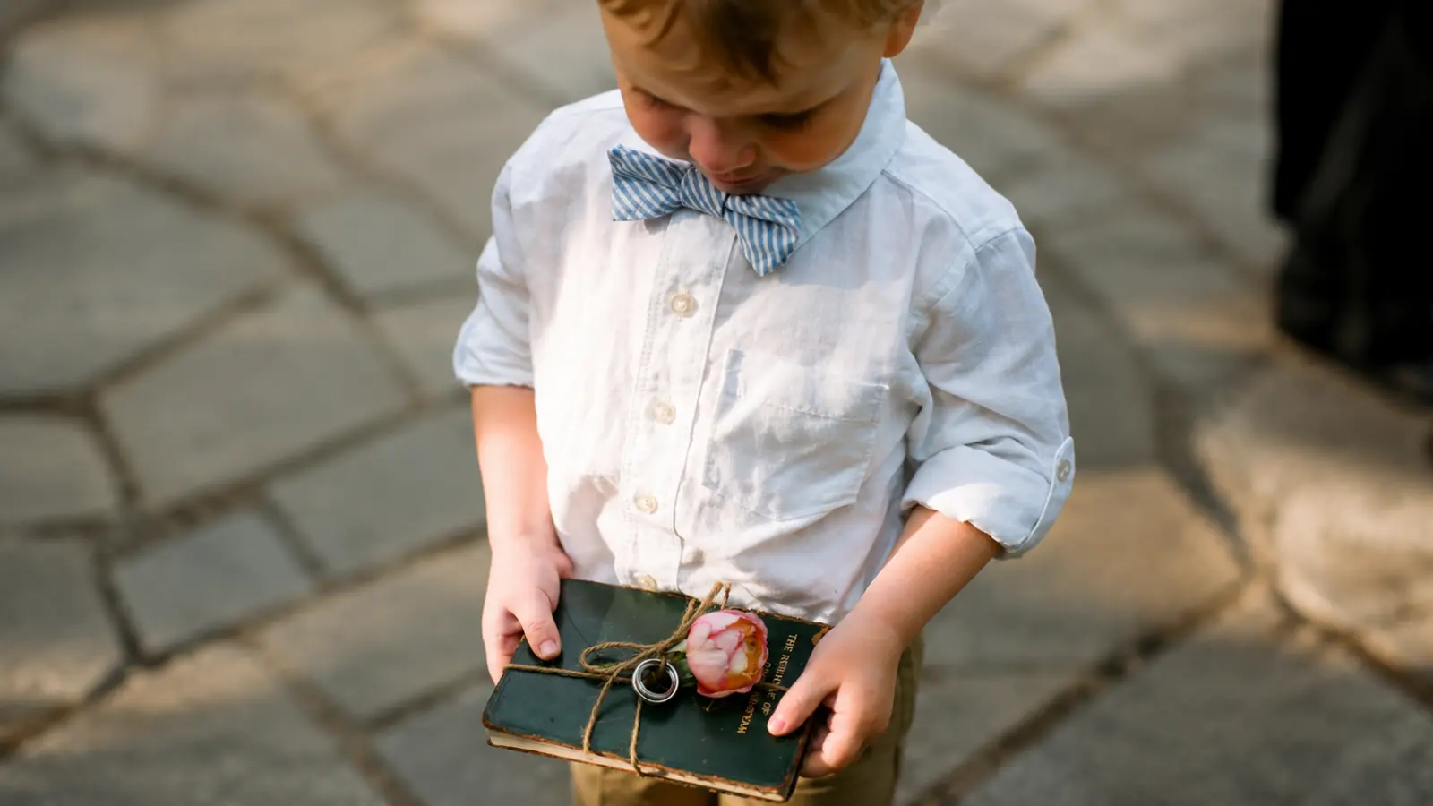 Young ring bearer carrying wedding rings tied to a vintage book with twine and a flower as a unique ring pillow alternative Ring Bearer Pillow and Box