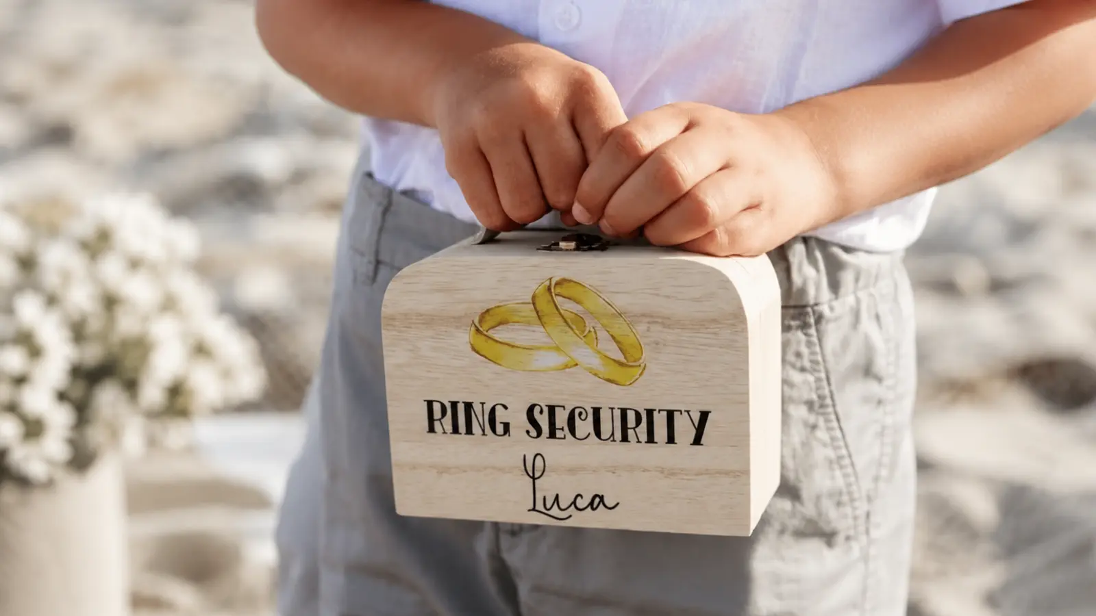 Child holding a personalized wooden Ring Security box decorated with wedding rings and his name as a ring bearer proposal gift