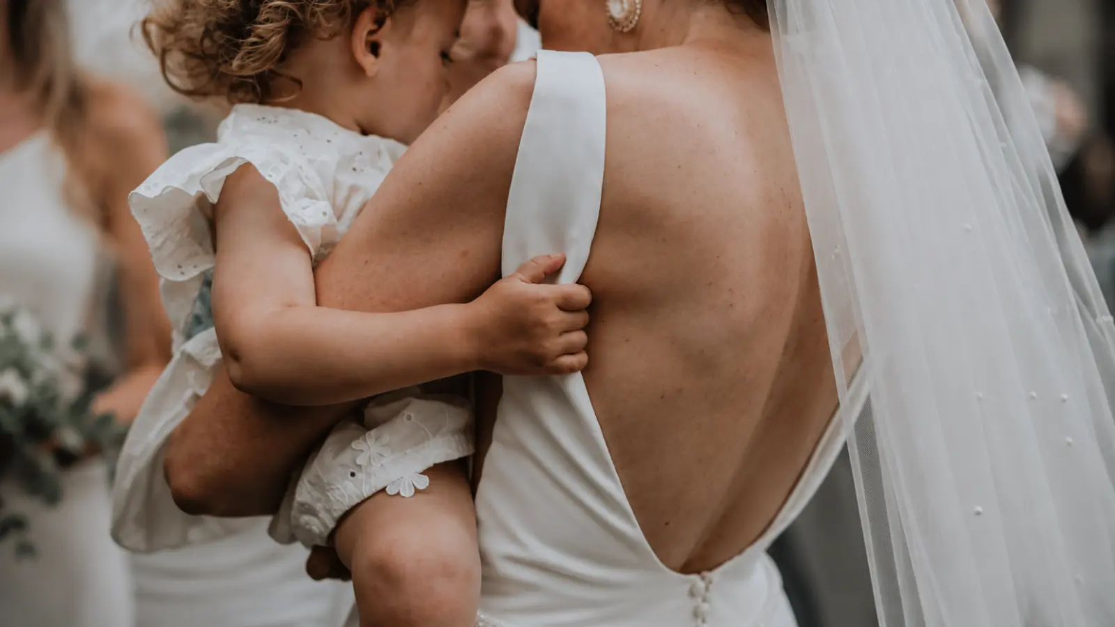 Should You Invite Children to Your Wedding represented by a bride holding a young child during the wedding celebration Should You Invite Children to Your Wedding? Guest List Options Explained