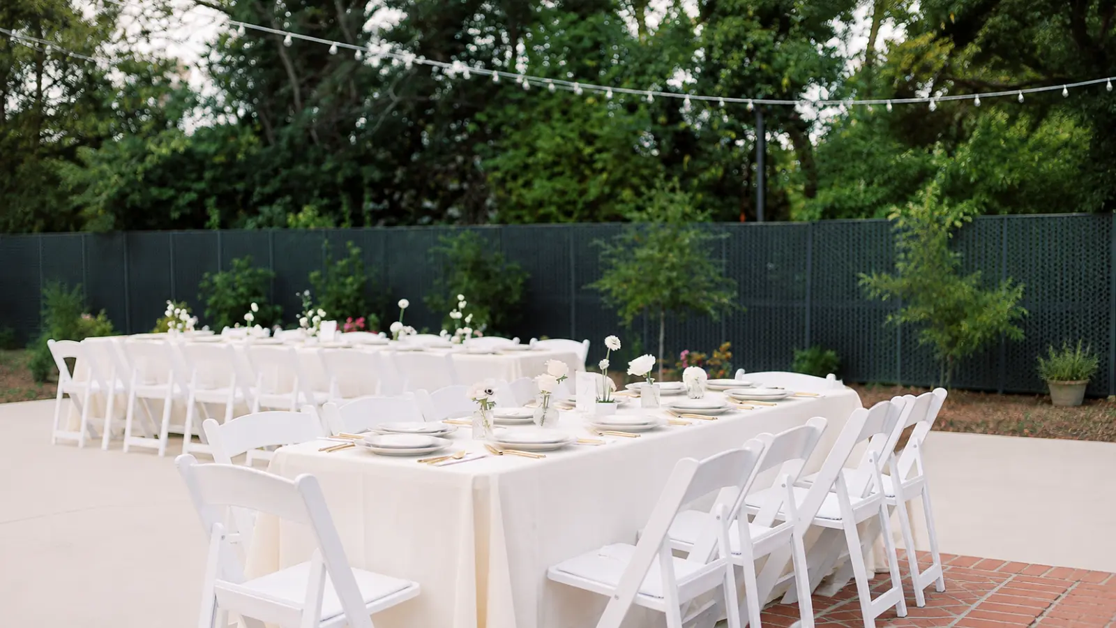 Outdoor wedding reception arranged with white tables, chairs and floral details after an organized and carefully managed wedding planning process