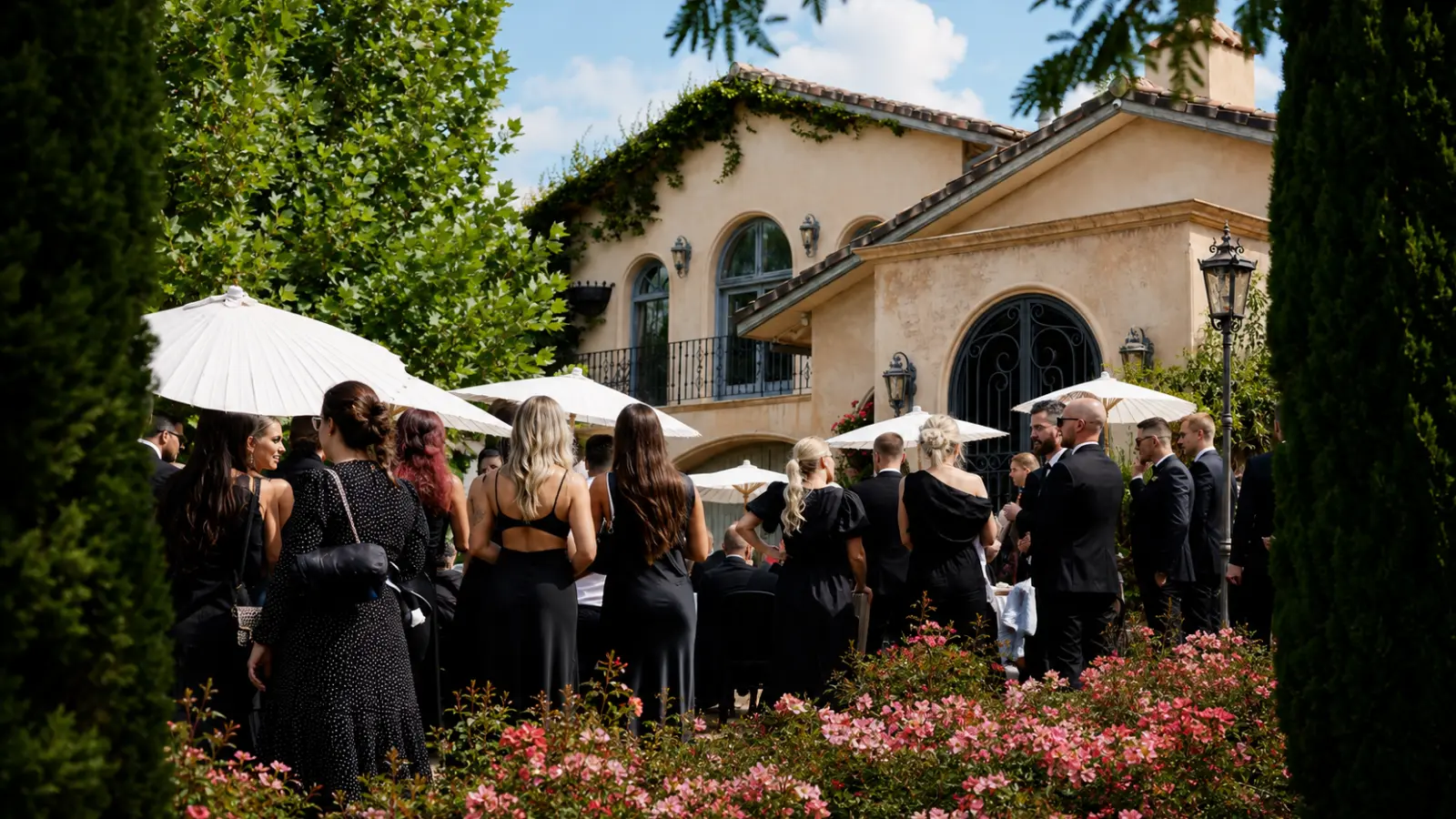 Elegantly dressed guests gathering outdoors at a private estate before a surprise wedding reveal How to Plan a Surprise Wedding Guests Won’t See Coming