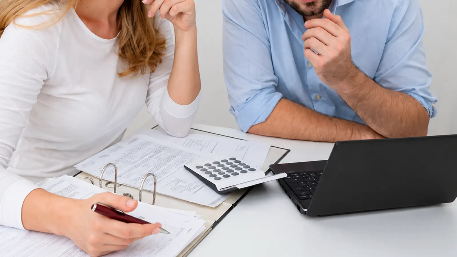 Married couple reviewing tax documents with a calculator and laptop while preparing tax updates after marriage Taxes After Marriage: Filing Status, W-4, Withholding and Tax Updates