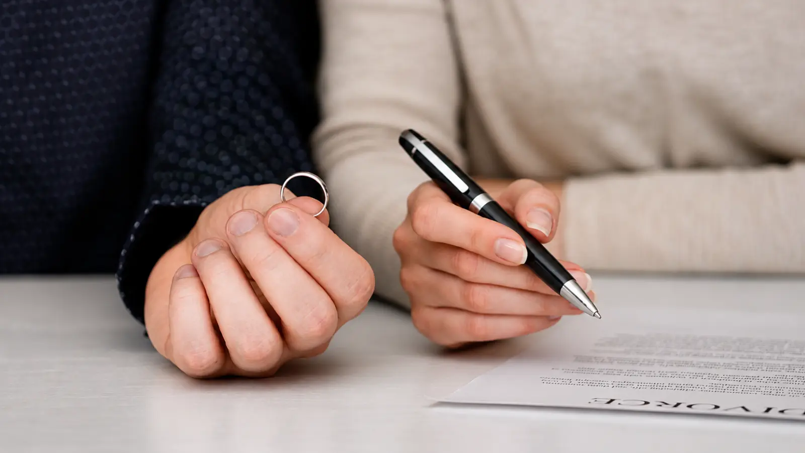 Spouses with divorce paperwork, pen and wedding ring, illustrating how an uncontested divorce works, its requirements and final steps Uncontested Divorce: How It Works, Requirements and Final Steps