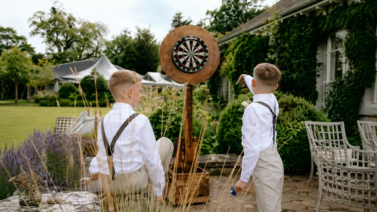 Two boys playing darts outdoors at a wedding reception, showing a fun activity that can keep older children entertained between important reception moments