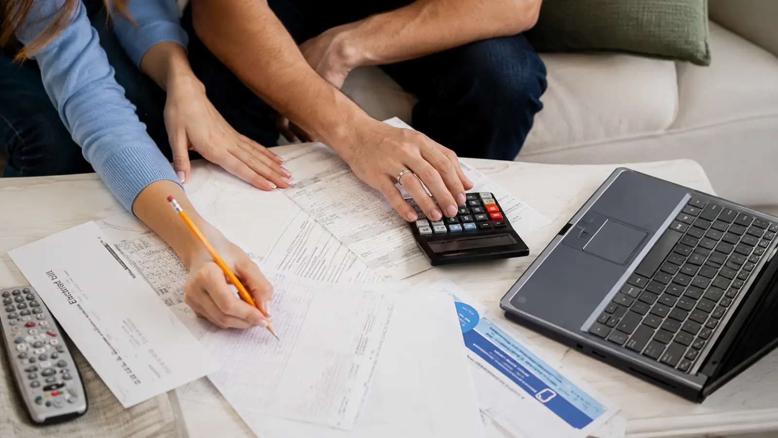 Wedding Budget Breakdown with a couple using a calculator and reviewing expense documents together to determine what percentage of their wedding budget to spend across major wedding categories