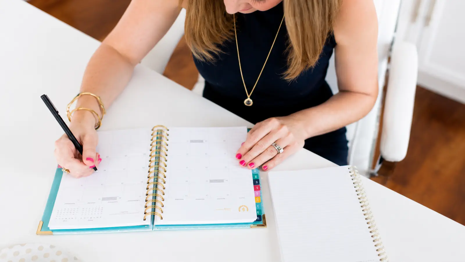 Woman writing in a planner while creating a wedding day timeline, organizing ceremony, reception, vendor and preparation times into a practical schedule that works