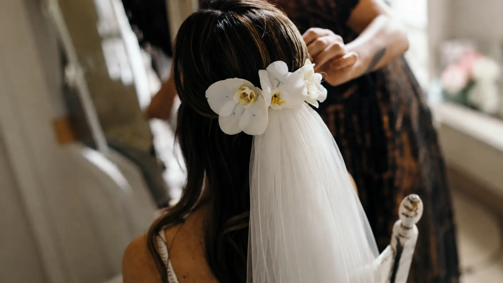 Bride having her hair styled with flowers and veil as part of a Wedding Morning Timeline for hair, makeup, getting ready, final beauty touches and pre-ceremony photos