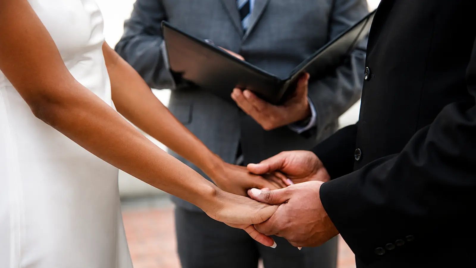 Wedding officiant leading a marriage ceremony while the couple holds hands, representing average officiant fees, services and possible extra costs Wedding Officiant Cost: Average Fees, Services and Extra Costs