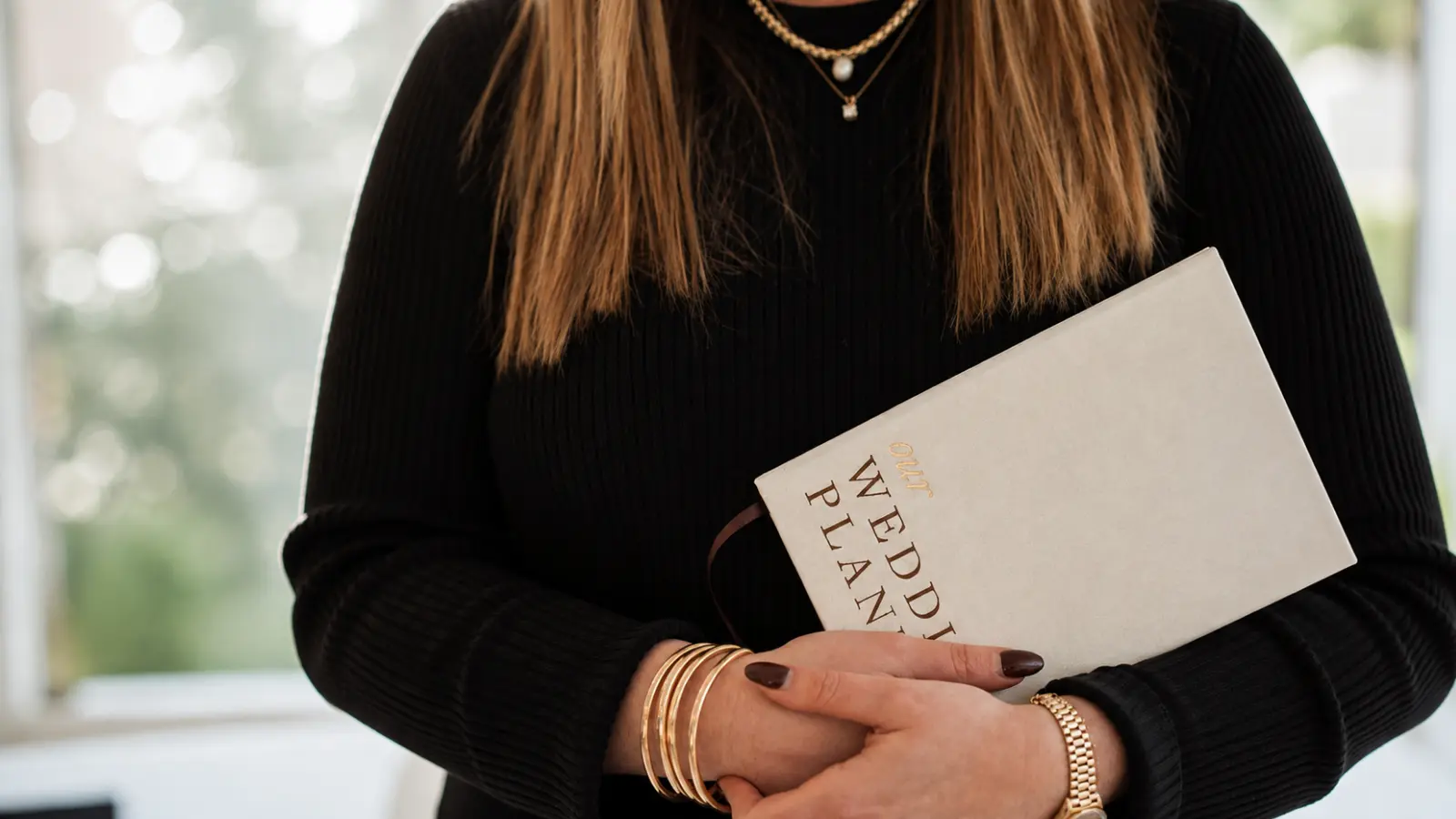 Wedding planner holding a wedding planning book representing the organized checklists, timelines, decisions and details involved in preparing a complete wedding plan