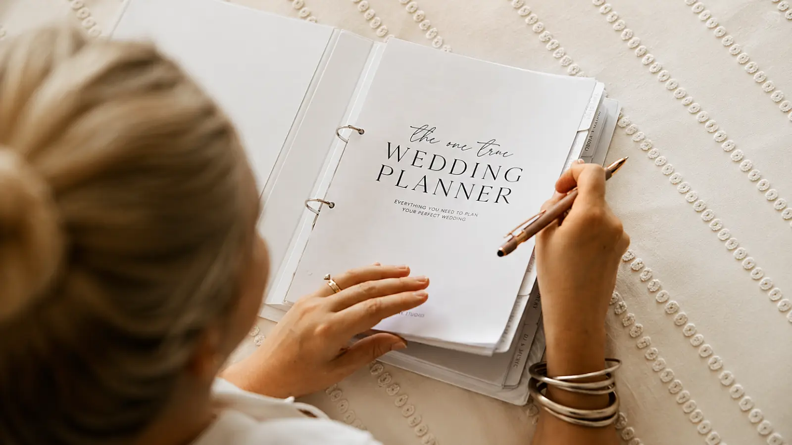 Wedding Planning Binder showing a bride organizing a physical wedding planner with divided sections for keeping wedding plans, documents and important details together Wedding Planning Binder: How to Organize a Physical Planner