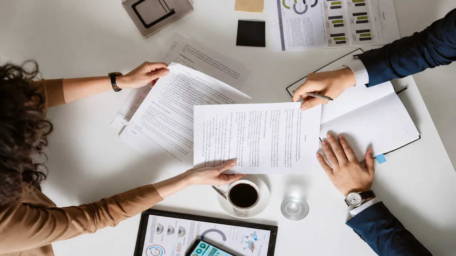 Two people reviewing documents and notes together while coordinating wedding planning roles and responsibilities before the wedding