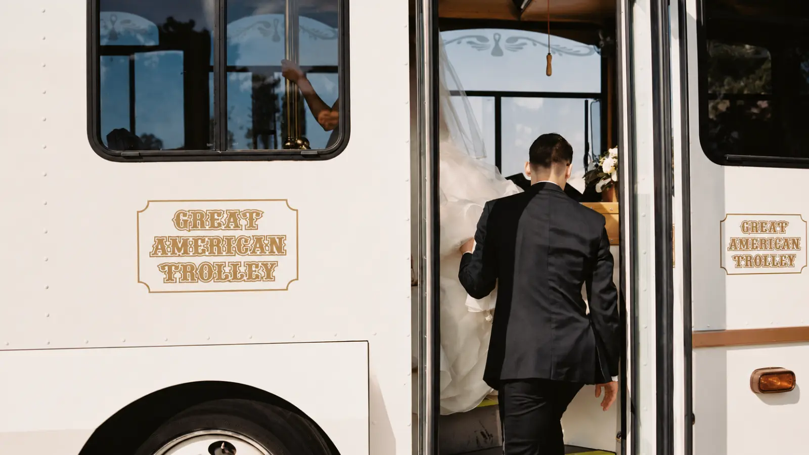Newlywed couple boarding a wedding trolley as part of their planned wedding day transportation