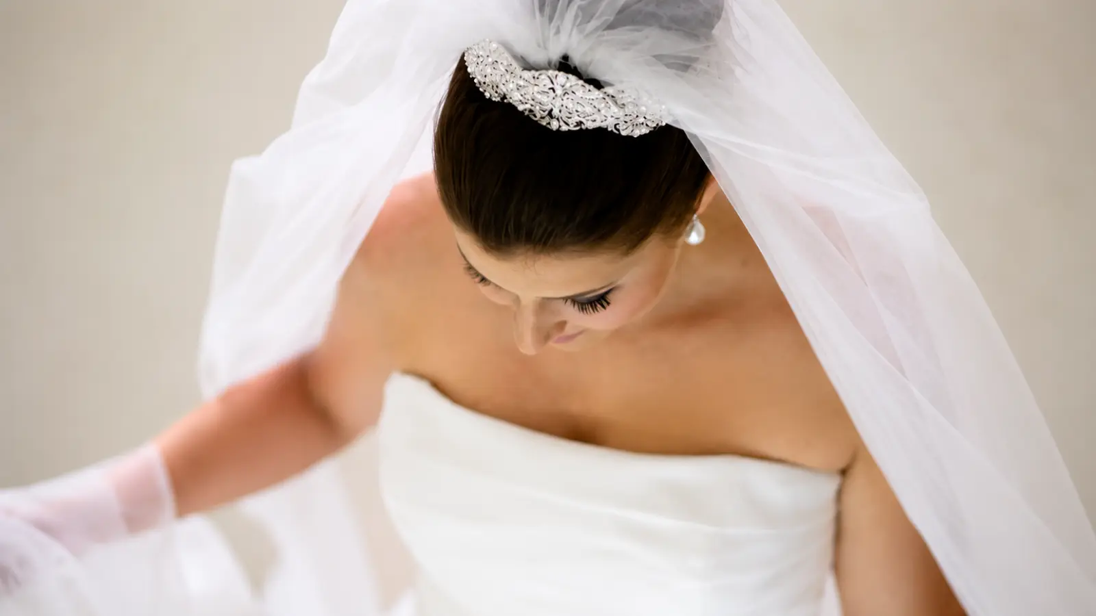 Bride viewed from above wearing a silver bridal tiara with a white tulle wedding veil and sleek dark hair Wedding Veil With Tiara