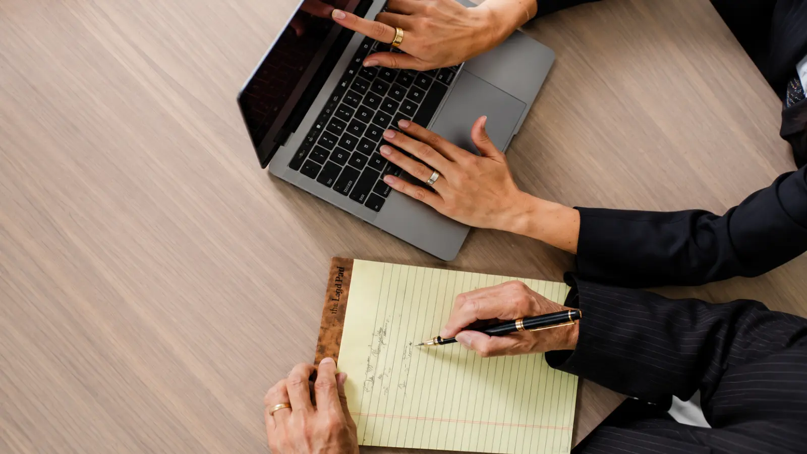 Wedding planning professionals using a laptop and taking notes while organizing the essential items, services and decisions needed for a complete wedding What Do You Need for a Wedding? Complete Essentials List