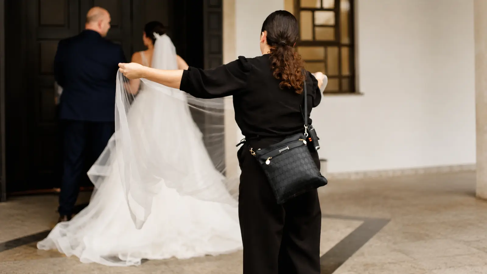 Wedding coordinator assists a bride with her veil while guiding the couple during the wedding day What Does a Wedding Coordinator Do? Before and During the Wedding