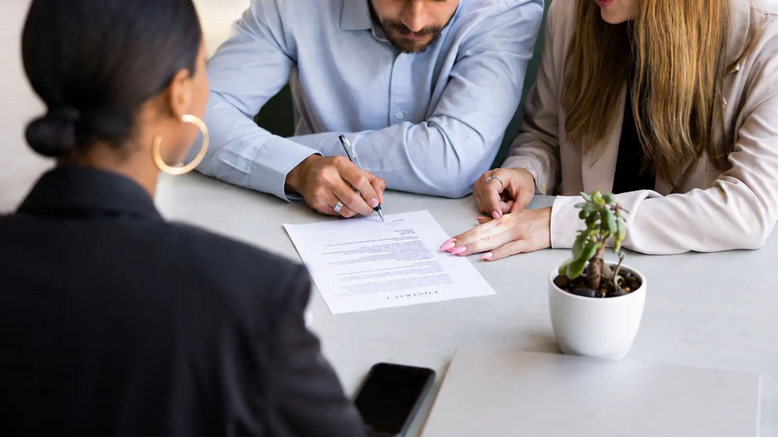 When to Book Wedding Vendors as an engaged couple reviews and signs a contract during a professional wedding planning meeting When to Book Wedding Vendors: Complete Booking Timeline