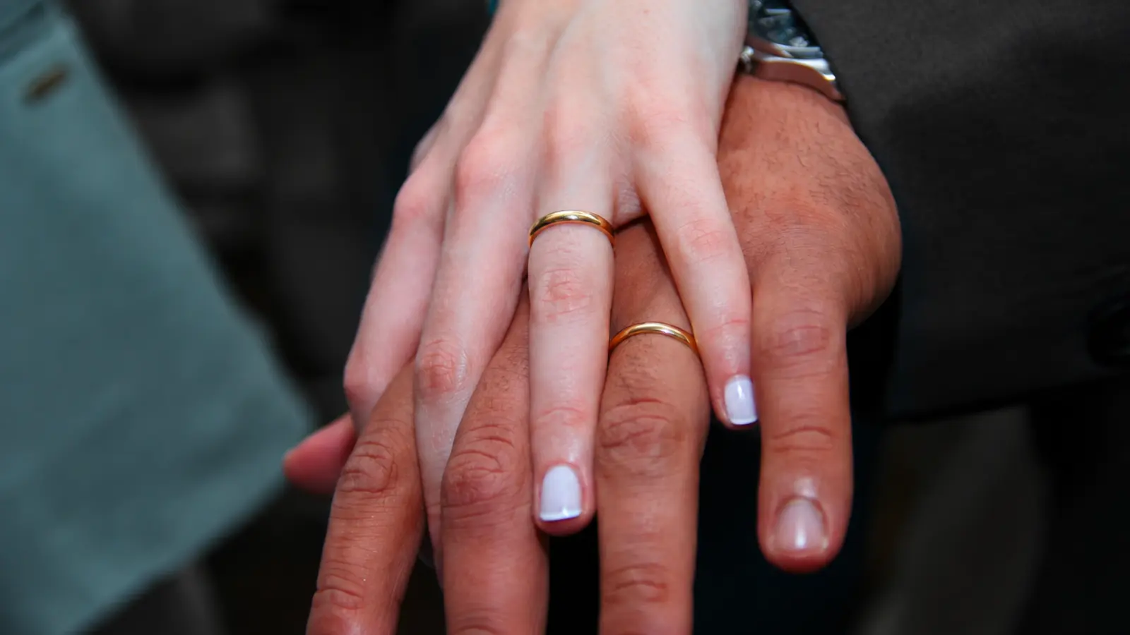Couple showing their wedding bands together as inspiration for meaningful 10th wedding anniversary jewelry gifts