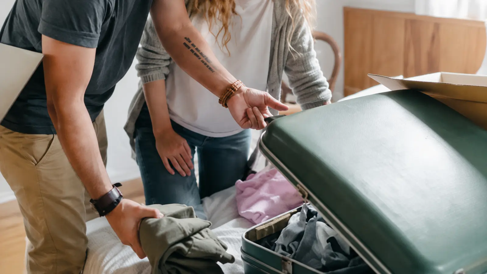 Couple packing a suitcase with clothing, illustrating travel-inspired and practical gift alternatives for celebrating a second wedding anniversary