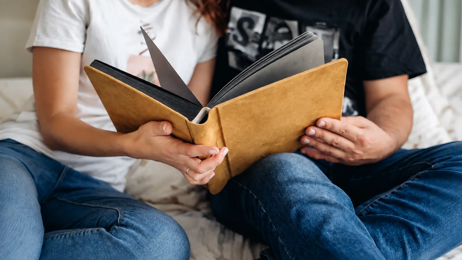 Couple looking through a leather photo album together, illustrating a sentimental leather gift filled with shared memories for a third wedding anniversary