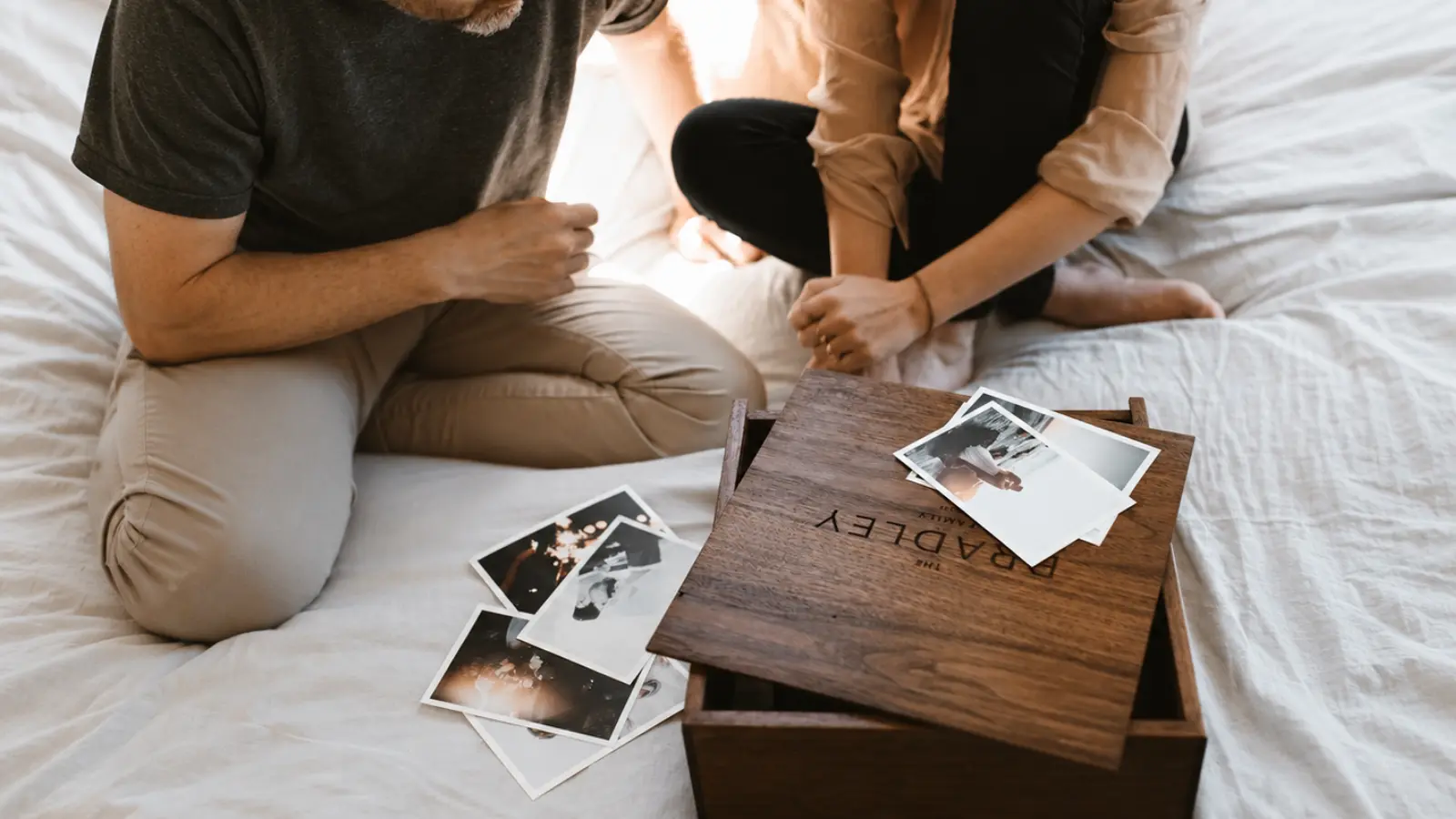 Couple looking through photographs beside a wooden memory box, illustrating a sentimental wood gift idea for celebrating five years of marriage