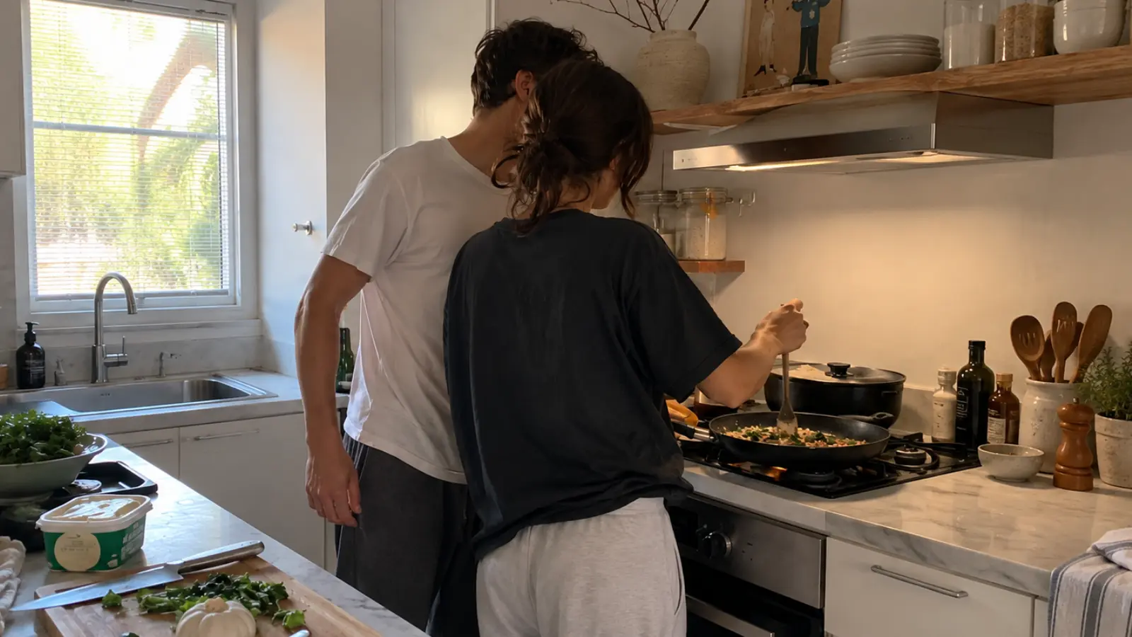 Couple cooking together with a cast iron skillet at home, illustrating a shared sixth wedding anniversary experience inspired by the traditional iron theme