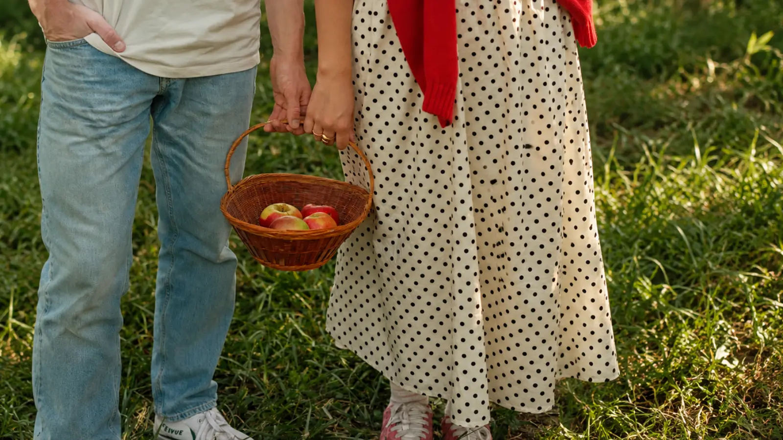 Couple carrying a woven basket filled with apples outdoors as inspiration for traditional willow 9th wedding anniversary gifts