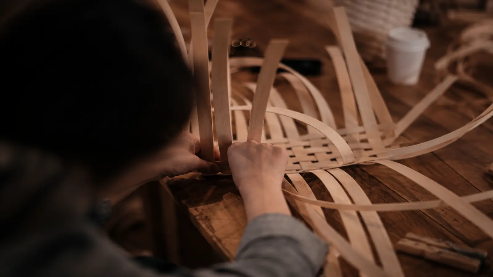 Artisan weaving natural willow strips by hand to create a traditional basket for a 9th wedding anniversary gift