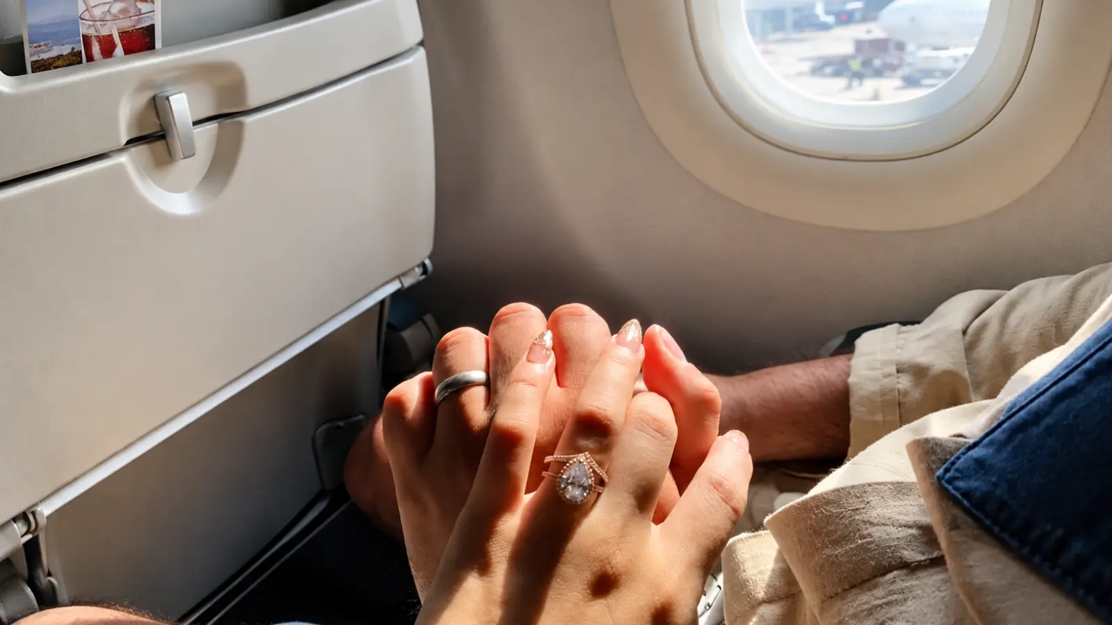Married couple wearing rings holding hands on an airplane, illustrating a meaningful wedding anniversary experience and celebration of another year together Wedding Anniversary Gifts by Year: Traditional, Modern, Gemstones and Flowers