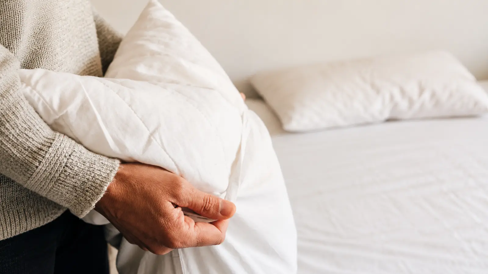 Person holding soft white bedding as a linen gift idea for a 12th wedding anniversary