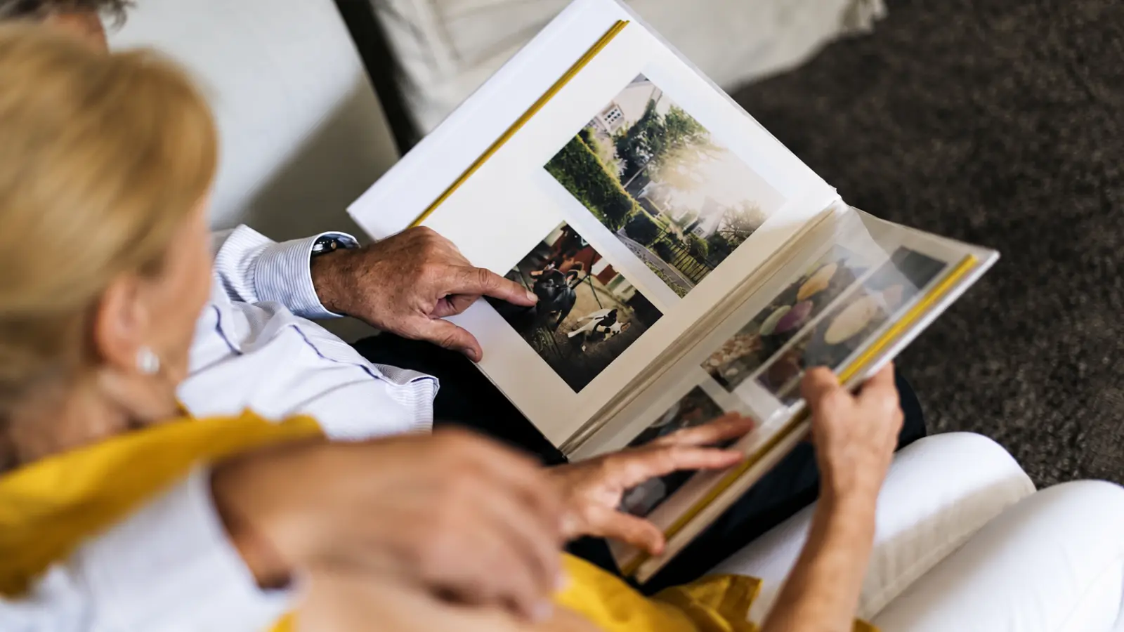 Couple looking through a photo album as a sentimental 13th wedding anniversary gift idea