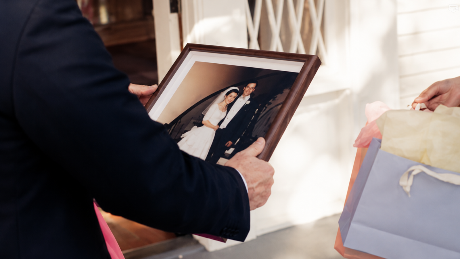 Person holding a wooden-framed wedding photograph showing a bride and groom, illustrating a personalized photo gift idea for the 23rd wedding anniversary traditionally associated with silver plate