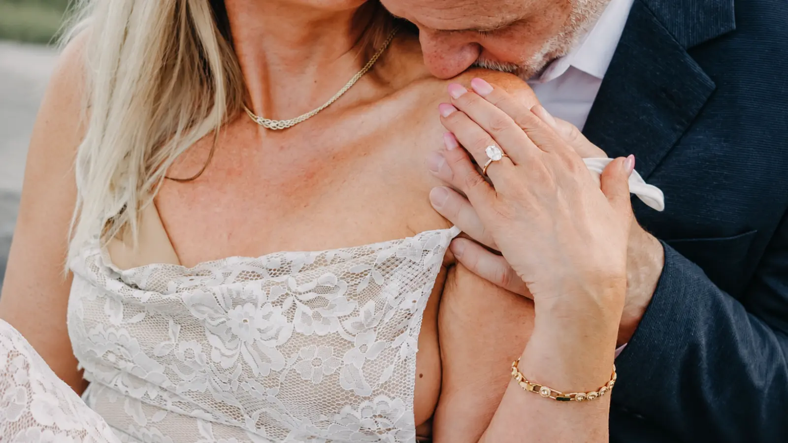 Mature couple sharing a romantic moment as a man gently kisses his partner's hand, with a gemstone ring and gold bracelet visible, representing thirty years of marriage 30th Wedding Anniversary: Pearl Gifts, Celebration Ideas and Meaning